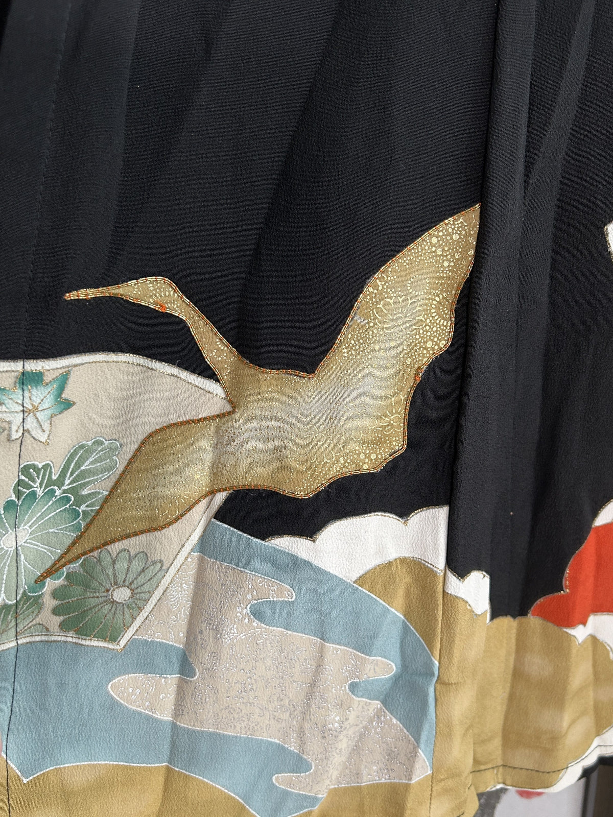 Gold flying bird above blue and beige shapes near skirt hem