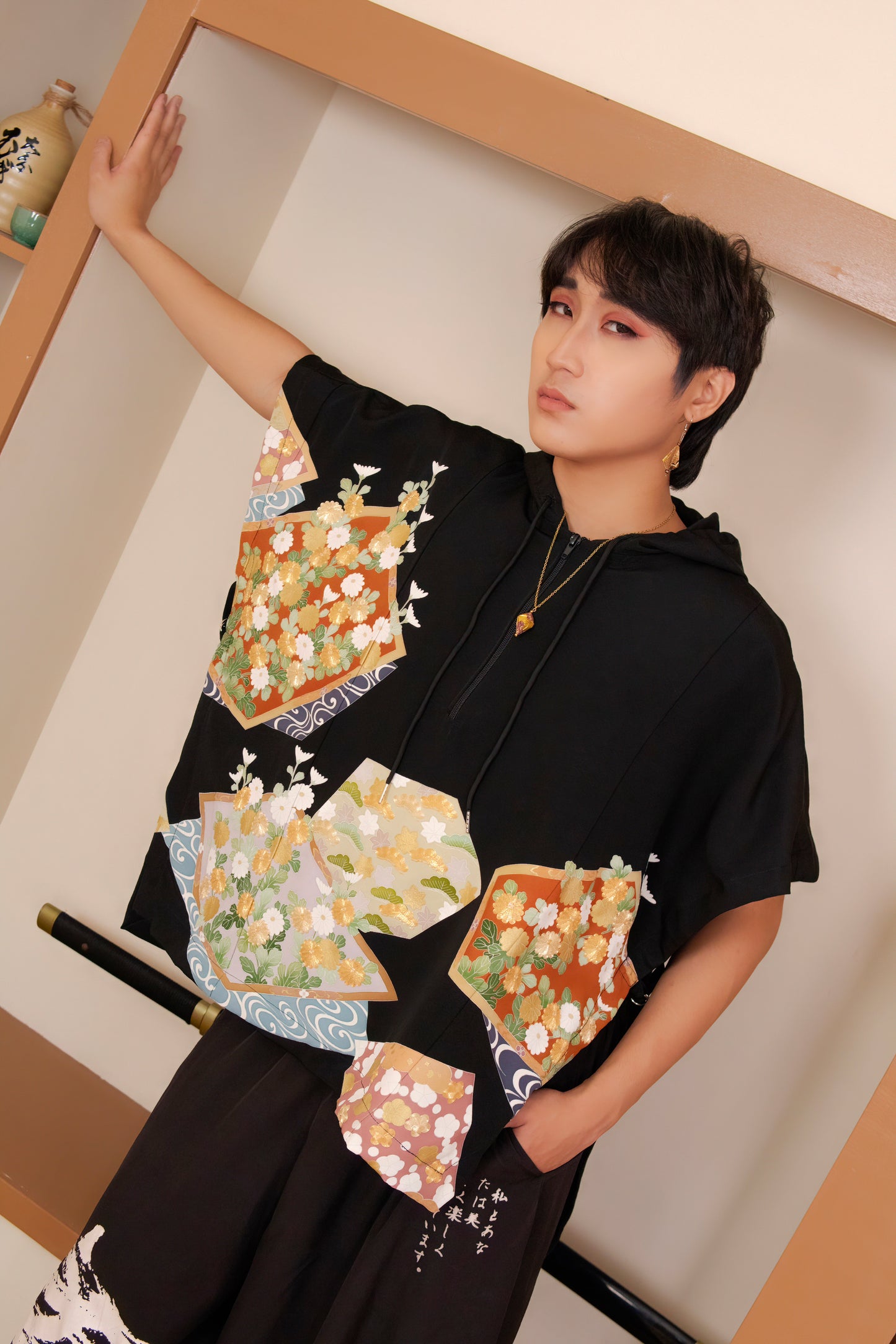 Person wearing a black kimono with colorful floral patterns in a minimal indoor setting