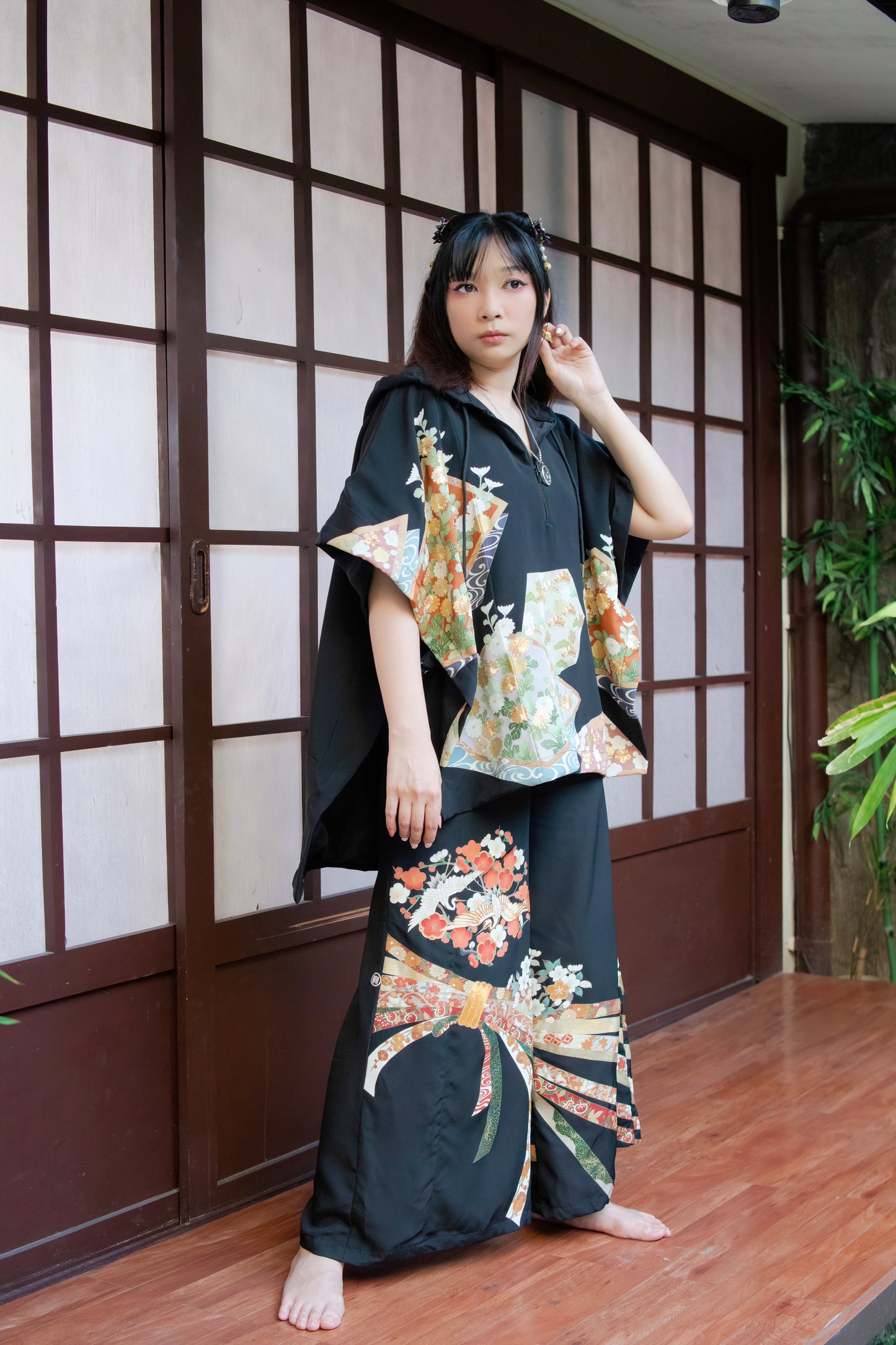 Woman wearing a traditional kimono with floral patterns in a room with wooden flooring and a sliding door.