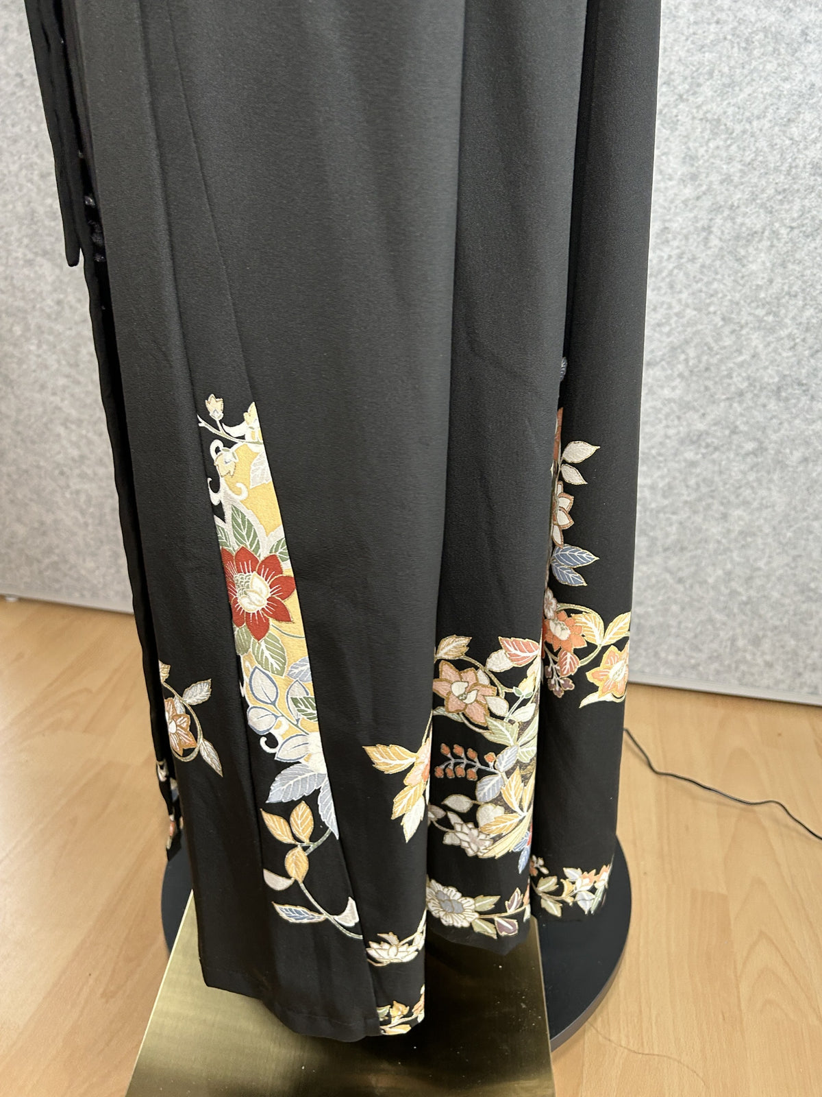 Black kimono dress hem with floral motifs, side view near the floor