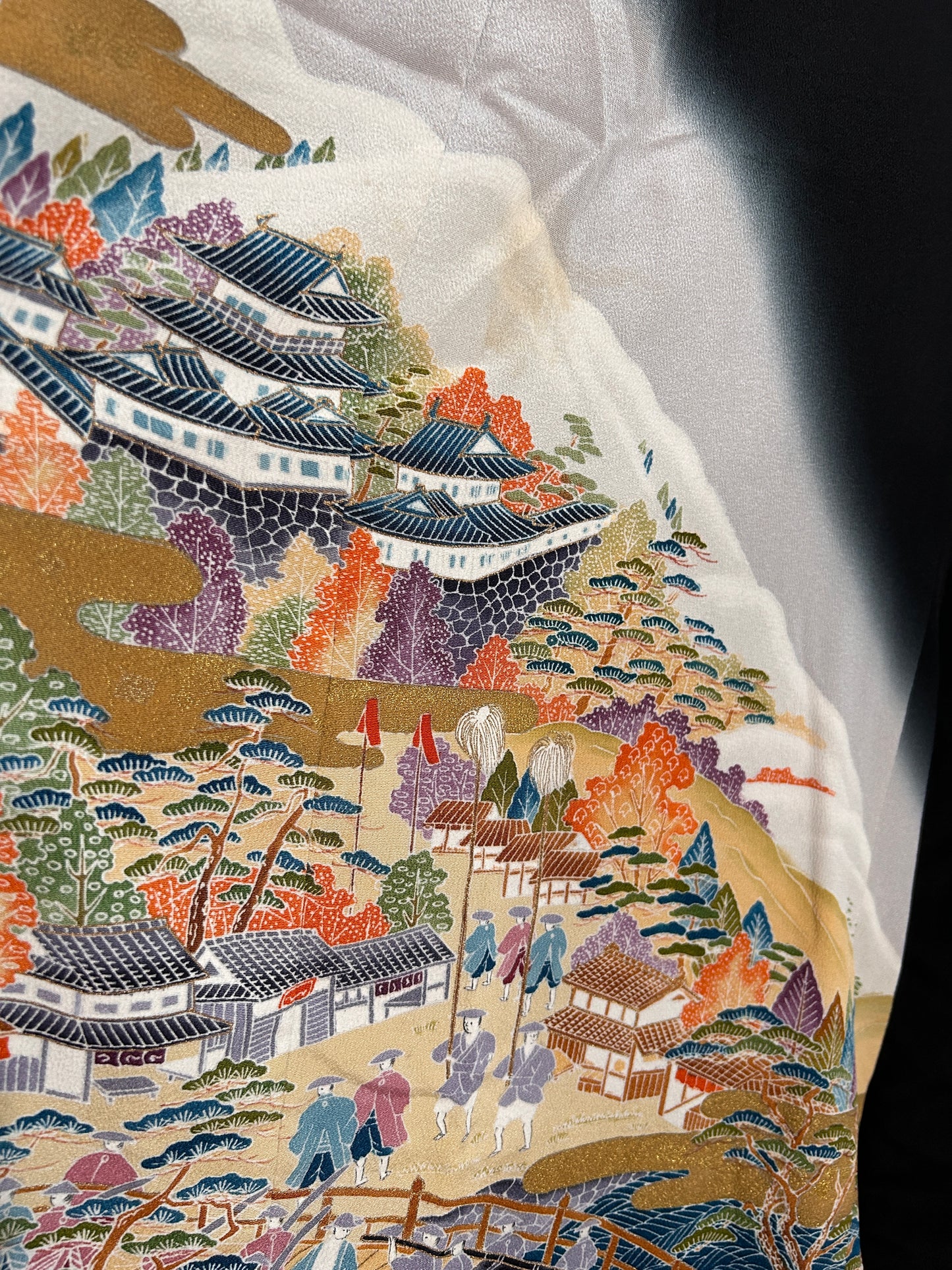 Close-up of a detailed embroidered fabric with floral and architectural patterns.