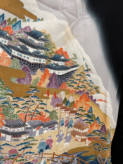Close-up of a detailed embroidered fabric with floral and architectural patterns.