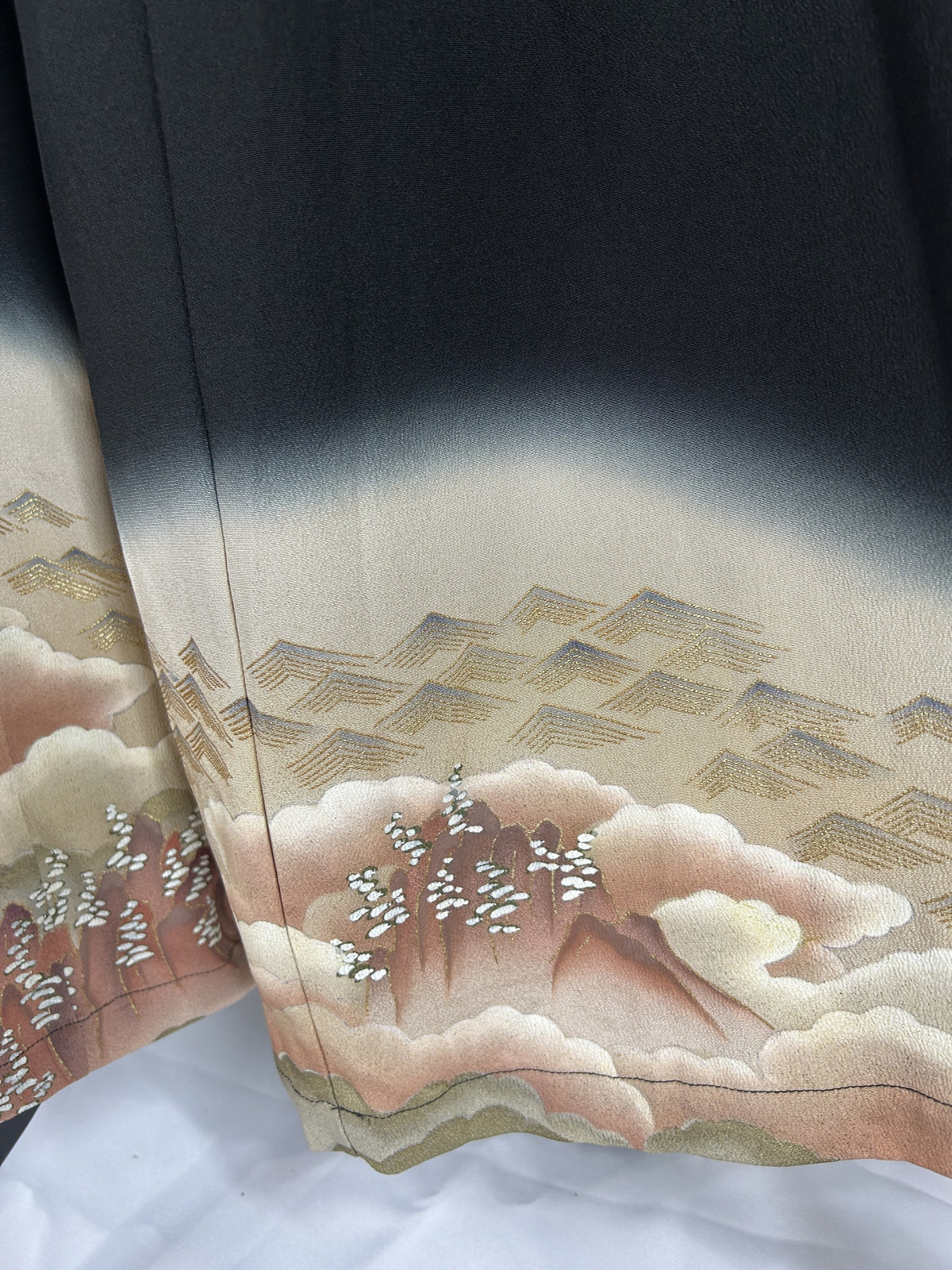 Black upcycled kimono palazzo pants, detail of the hem with clouds, hills and gold rooftops
