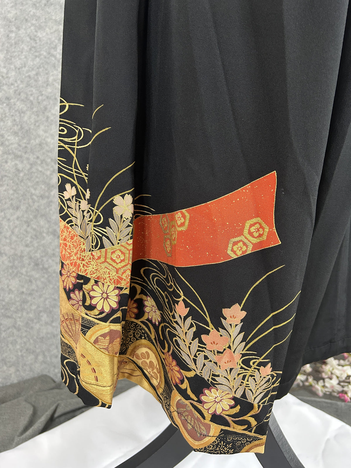 Black upcycled kimono palazzo pants, detail of the hem with orange-red band and grasses