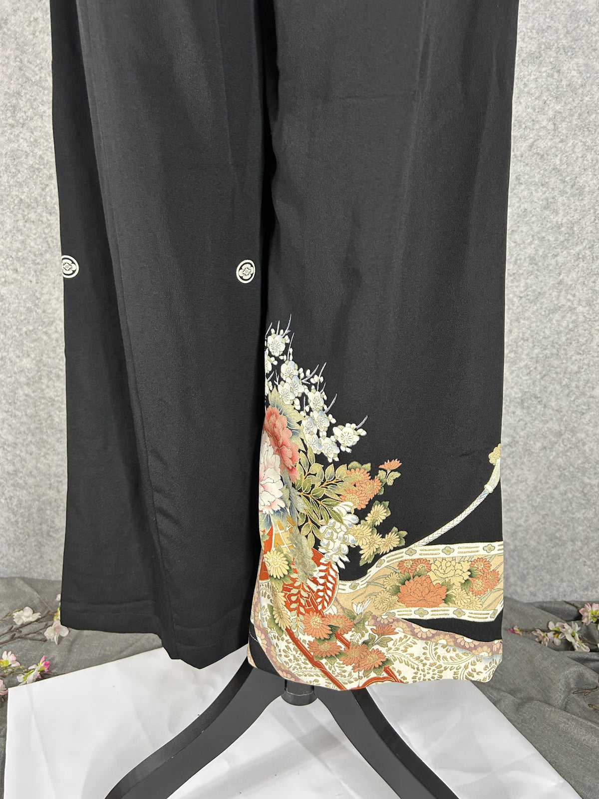 Black upcycled tomesode kimono wide leg pants with peonies, plum blossoms and white cords, back view with family crests