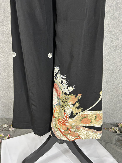 Black upcycled tomesode kimono wide leg pants with peonies, plum blossoms and white cords, back view with family crests
