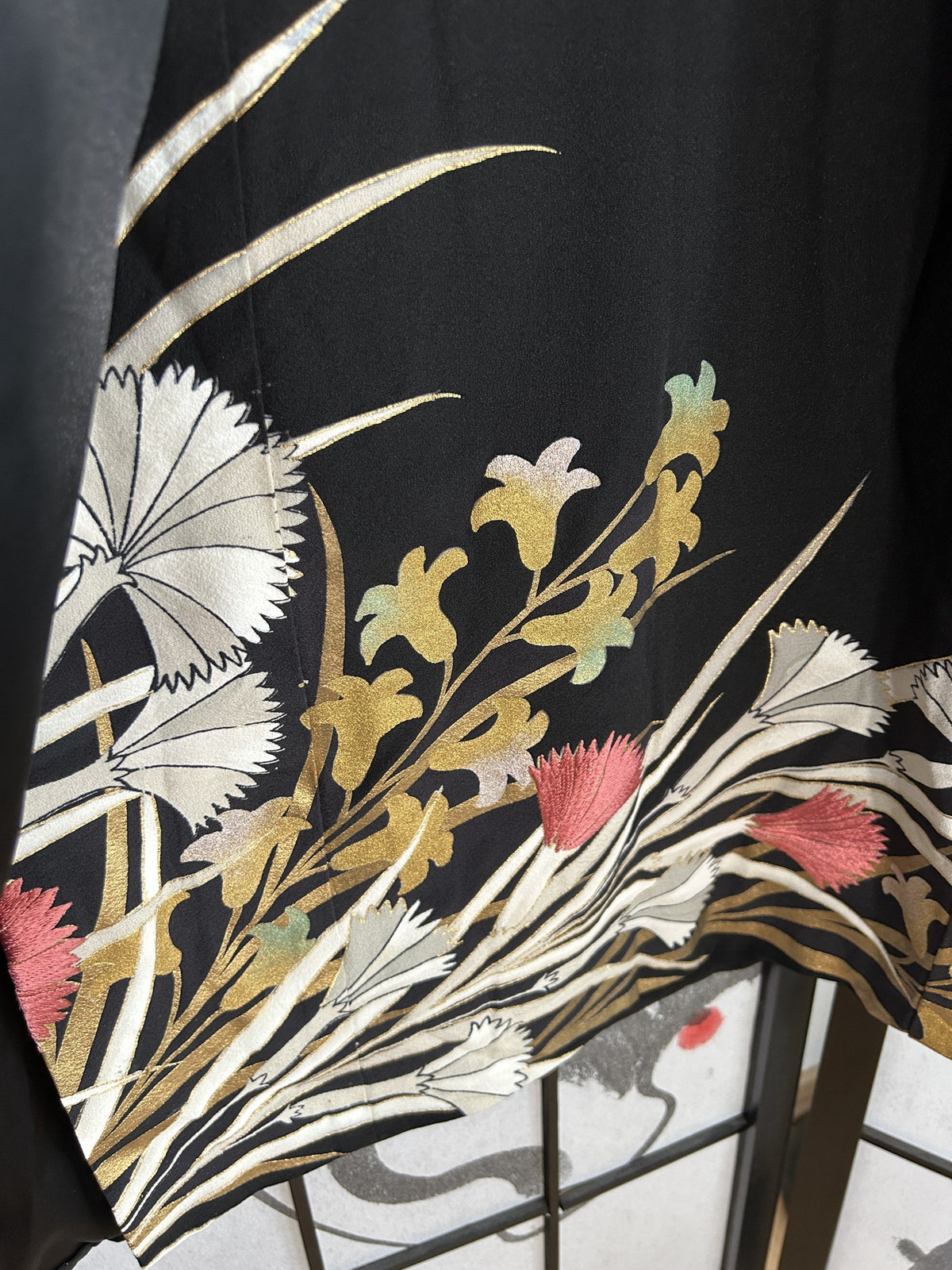 Black kimono wrap skirt, close-up of gold and white flowers near hem