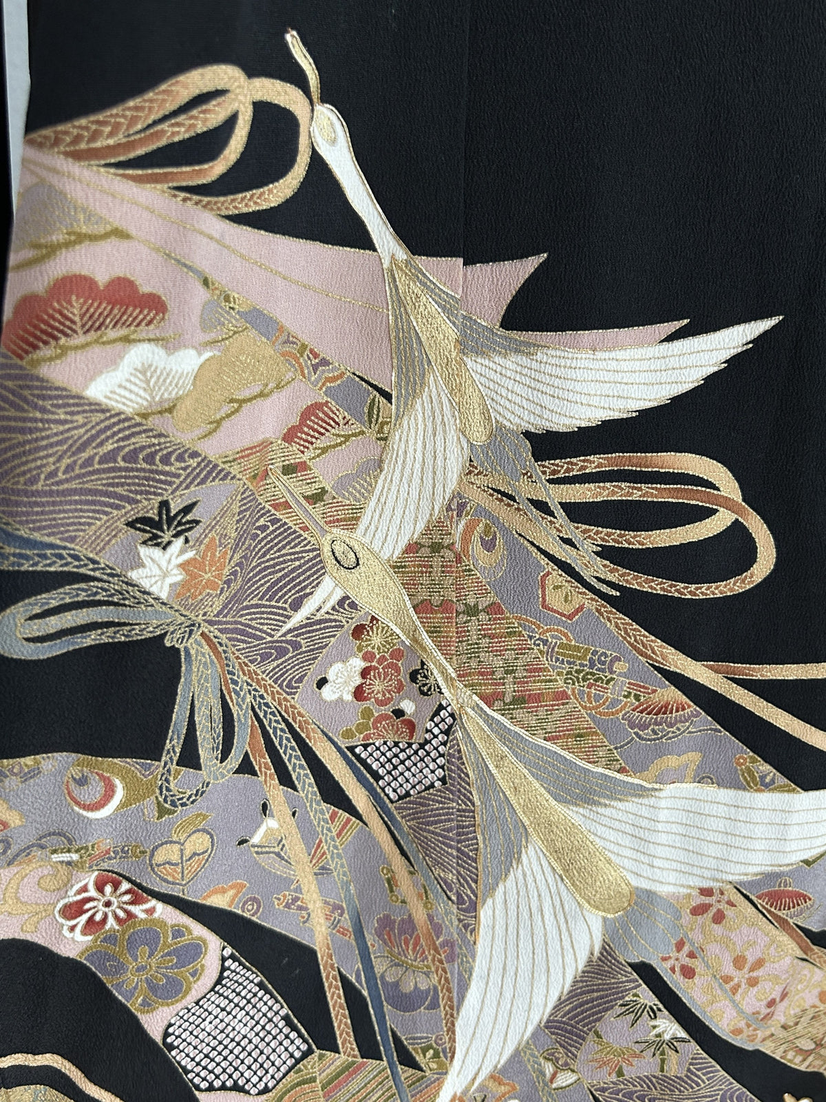 Black kimono wrap skirt, close-up of white cranes over lilac patterned bands