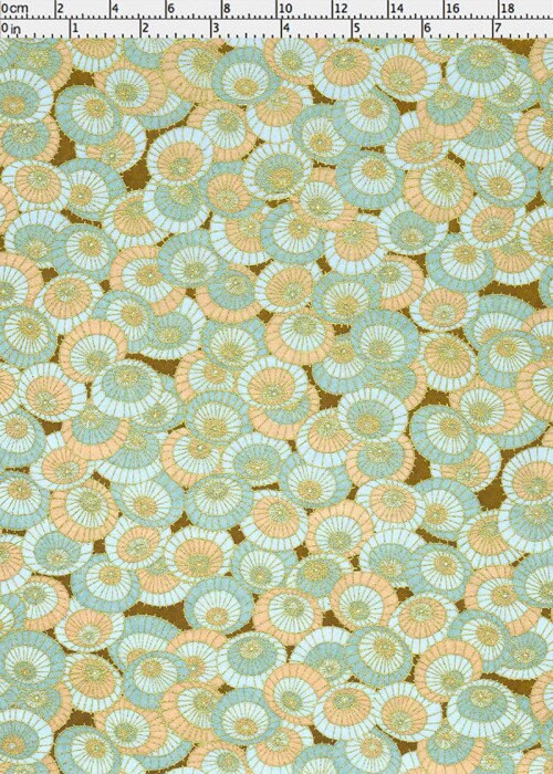 Patterned chiyogami paper with circular designs in green and orange on a brown background, with a ruler for scale.