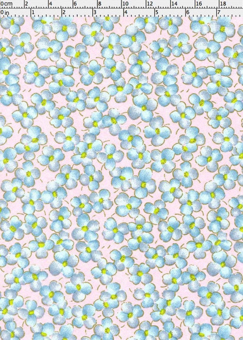Chiyogami paper with Pattern of small blue flowers with green centers on a pink background with a ruler for scale