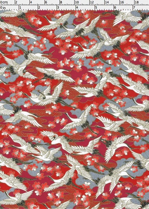 Chiyogami paper with crane and cherry blossom pattern on a red background with a ruler for scale
