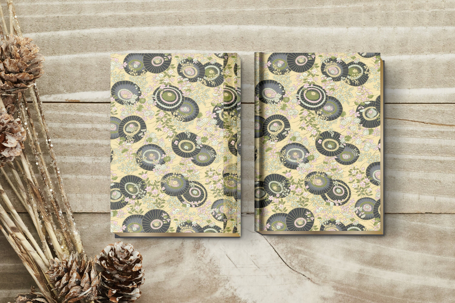 Two patterned notebooks made with chiyogami paper in a bookbinding project on a wooden surface with decorative elements.