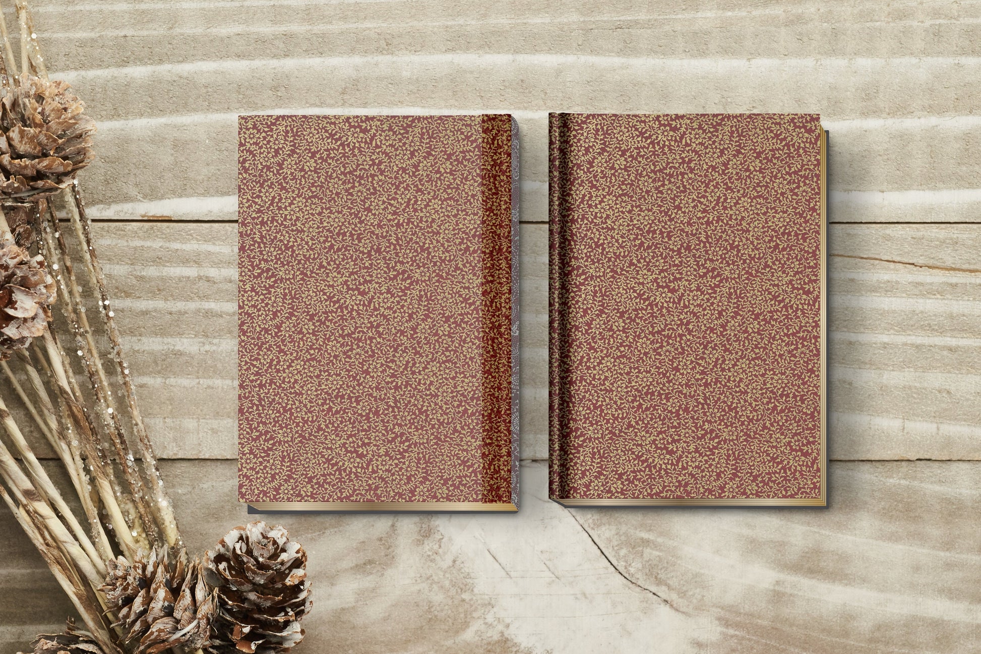 Two brown textured books on a wooden surface with dried plants.