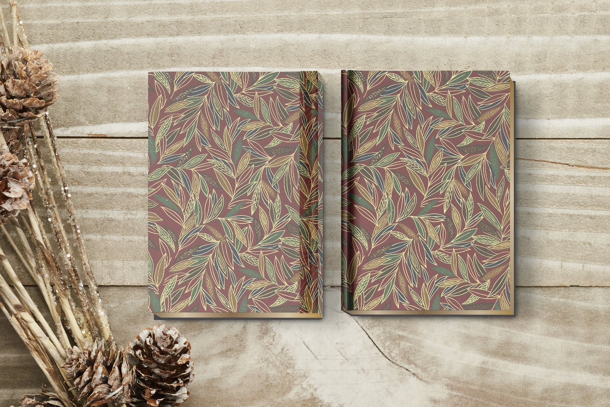 Two patterned books on a wooden surface with pine cones.