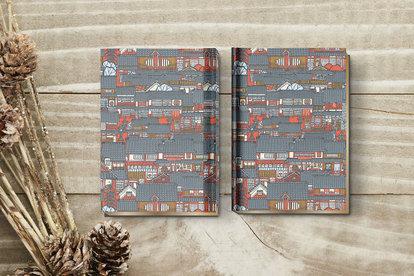 Two patterned books made with chiyogami paper in a bookbinding project on a wooden surface with decorative elements.
