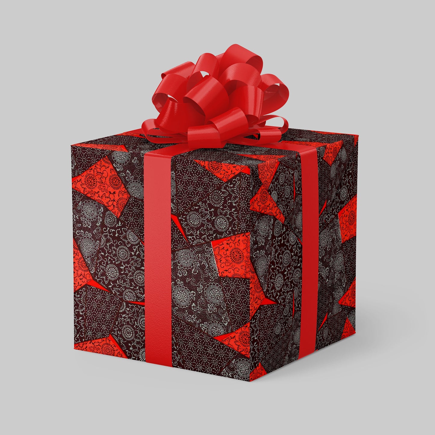 Gift box wrapped with chiyogami paper with red pattern and bow on a gray background