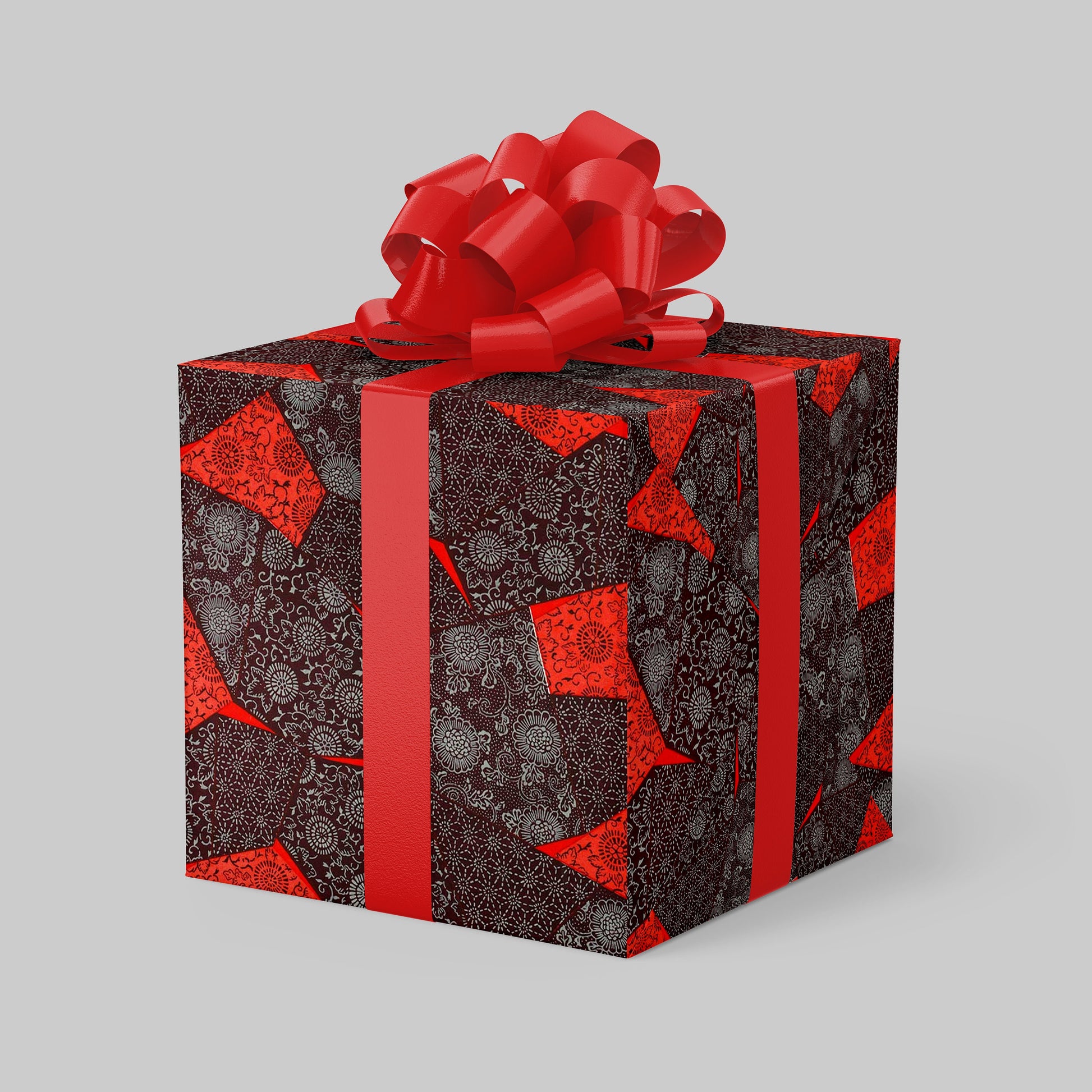 Gift box wrapped with chiyogami paper with red pattern and bow on a gray background