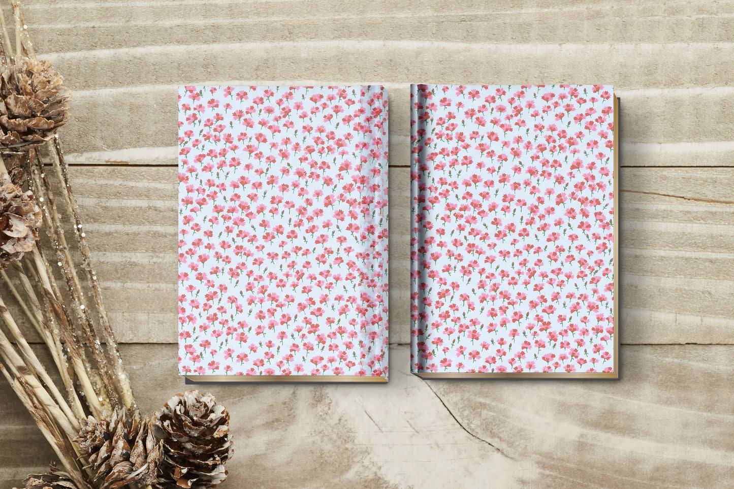 Two notebooks with floral pattern on a wooden surface with dried plants.