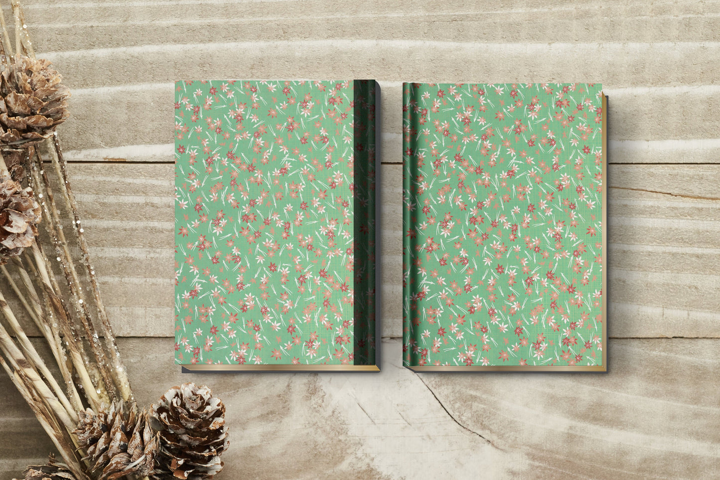 Two green notebooks made with chiyogami paper in a bookbinding project with floral patterns on a wooden surface.