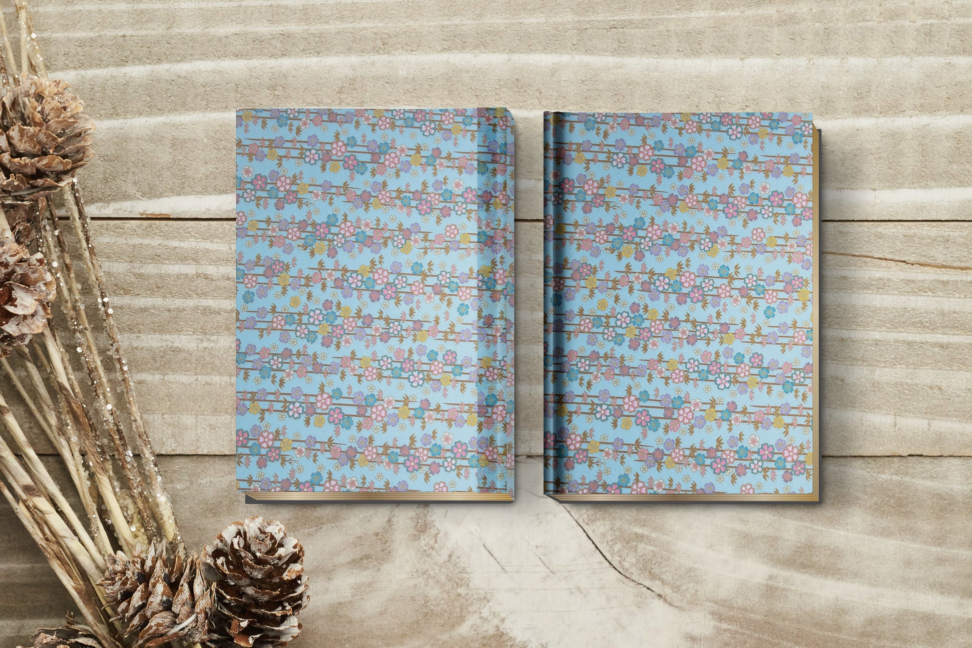 Two patterned notebooks made with chiyogami paper in a bookbinding project on a wooden surface with decorative elements.