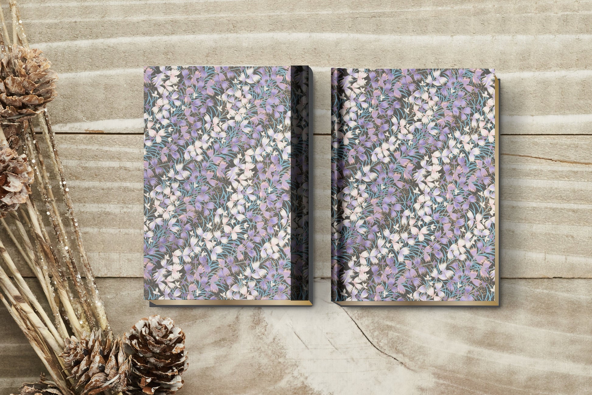 Two floral-patterned notebooks on a wooden surface with dried plants.