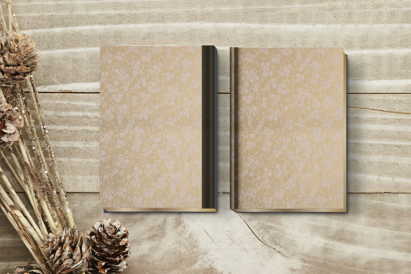 Two beige patterned books made with chiyogami paper in a bookbinding project on a wooden surface with dried plants.