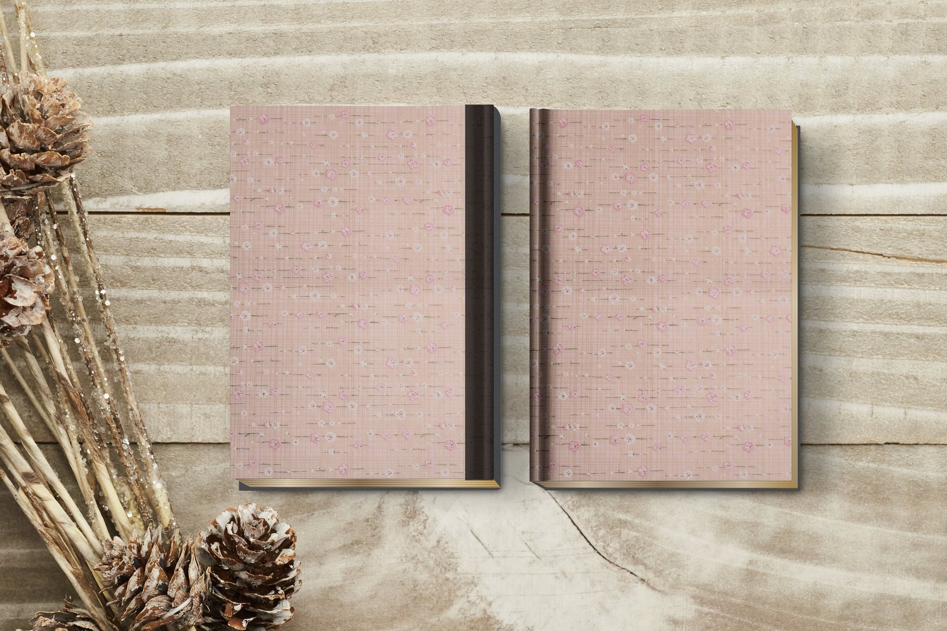 Two pink textured books made with chiyogami paper in a bookbinding project on a wooden surface with decorative elements.