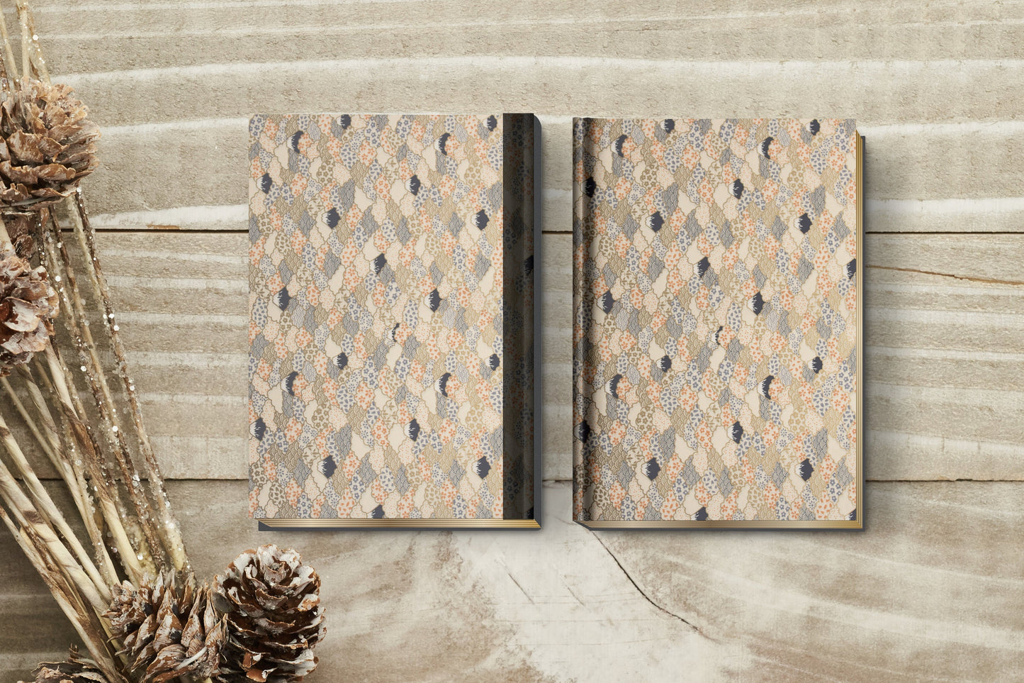 Two patterned books made with chiyogami paper in a bookbinding project on a wooden surface with decorative elements.