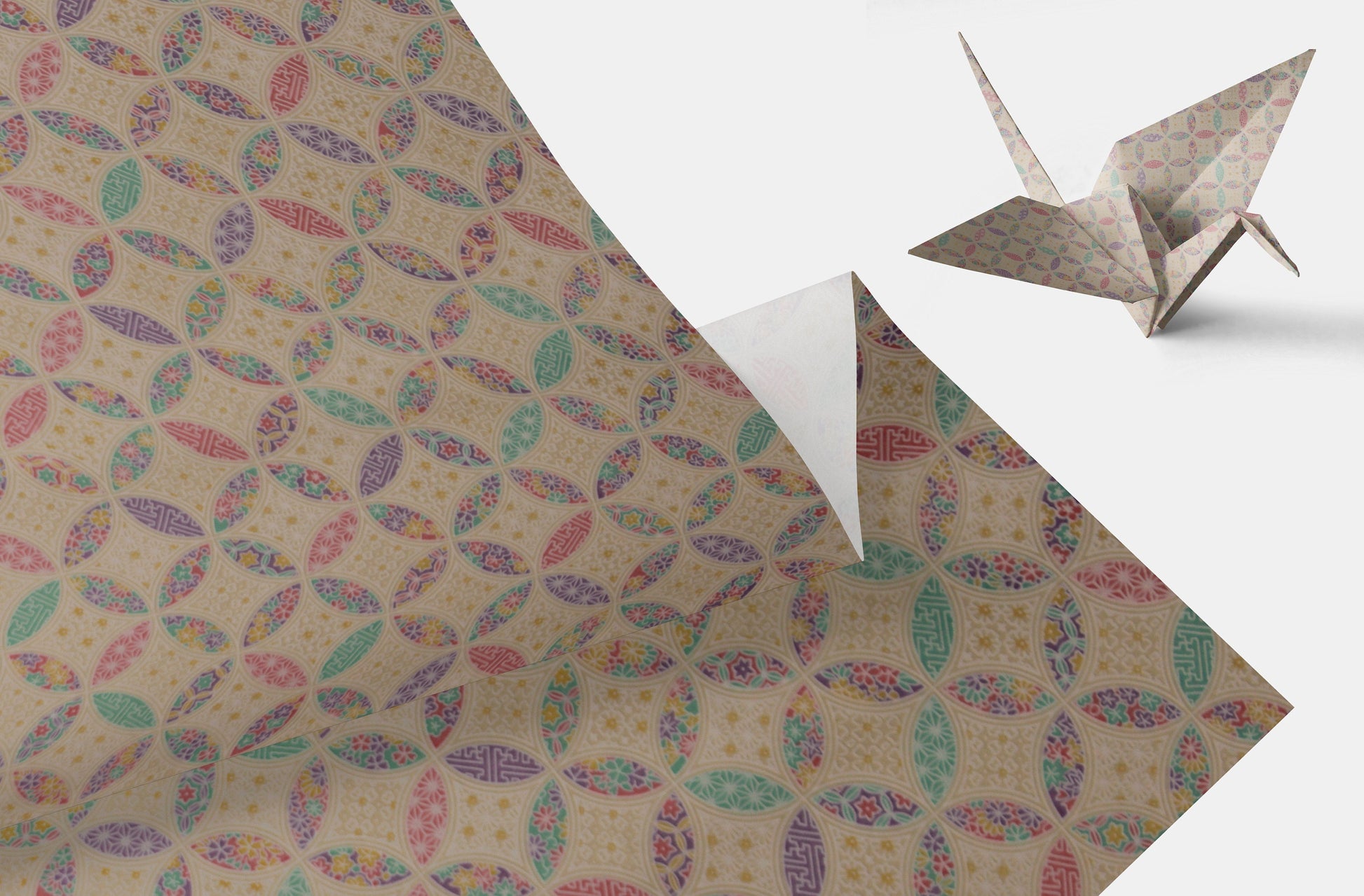 Patterned chiyogami paper with colorful designs and a folded paper crane on a white background