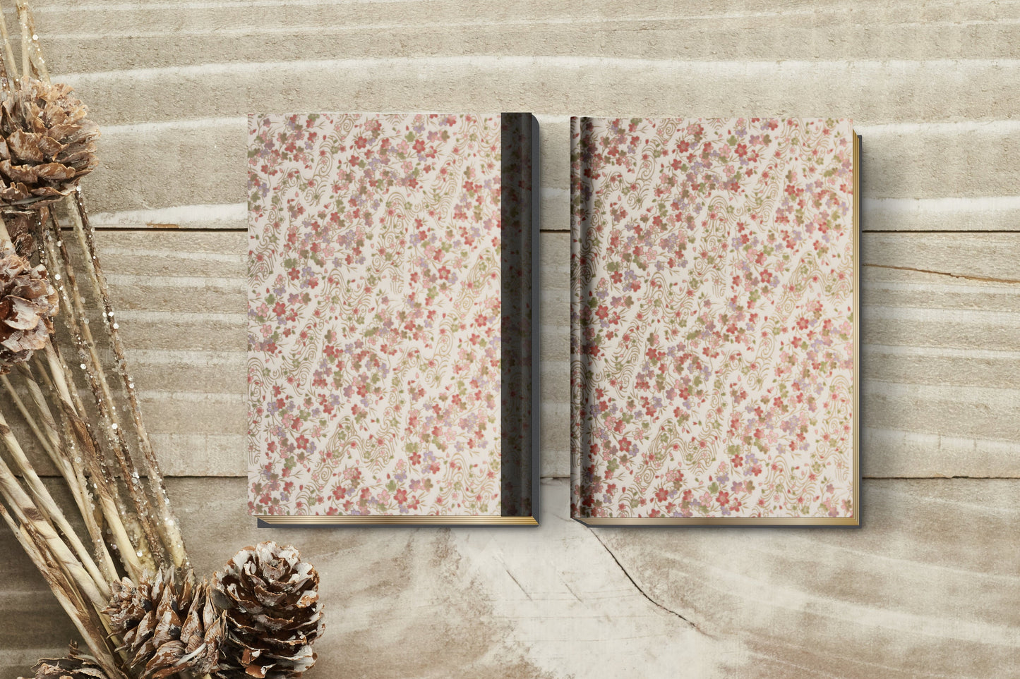Two floral-patterned notebooks made with chiyogami paper in a bookbinding project on a wooden surface with dried plants.