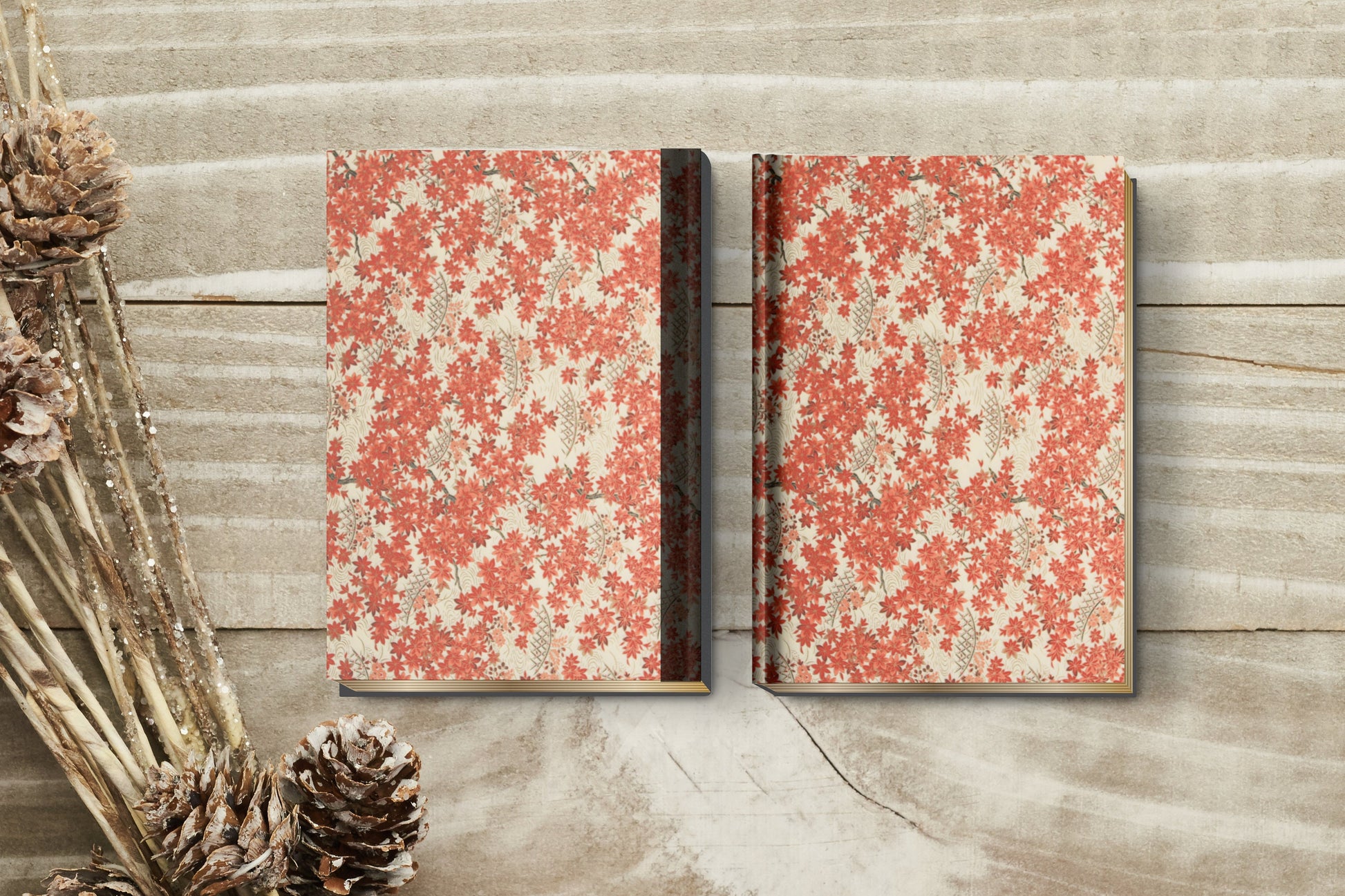 Two floral-patterned notebooks made with chiyogami paper as bookbinding project on a wooden surface with decorative elements.