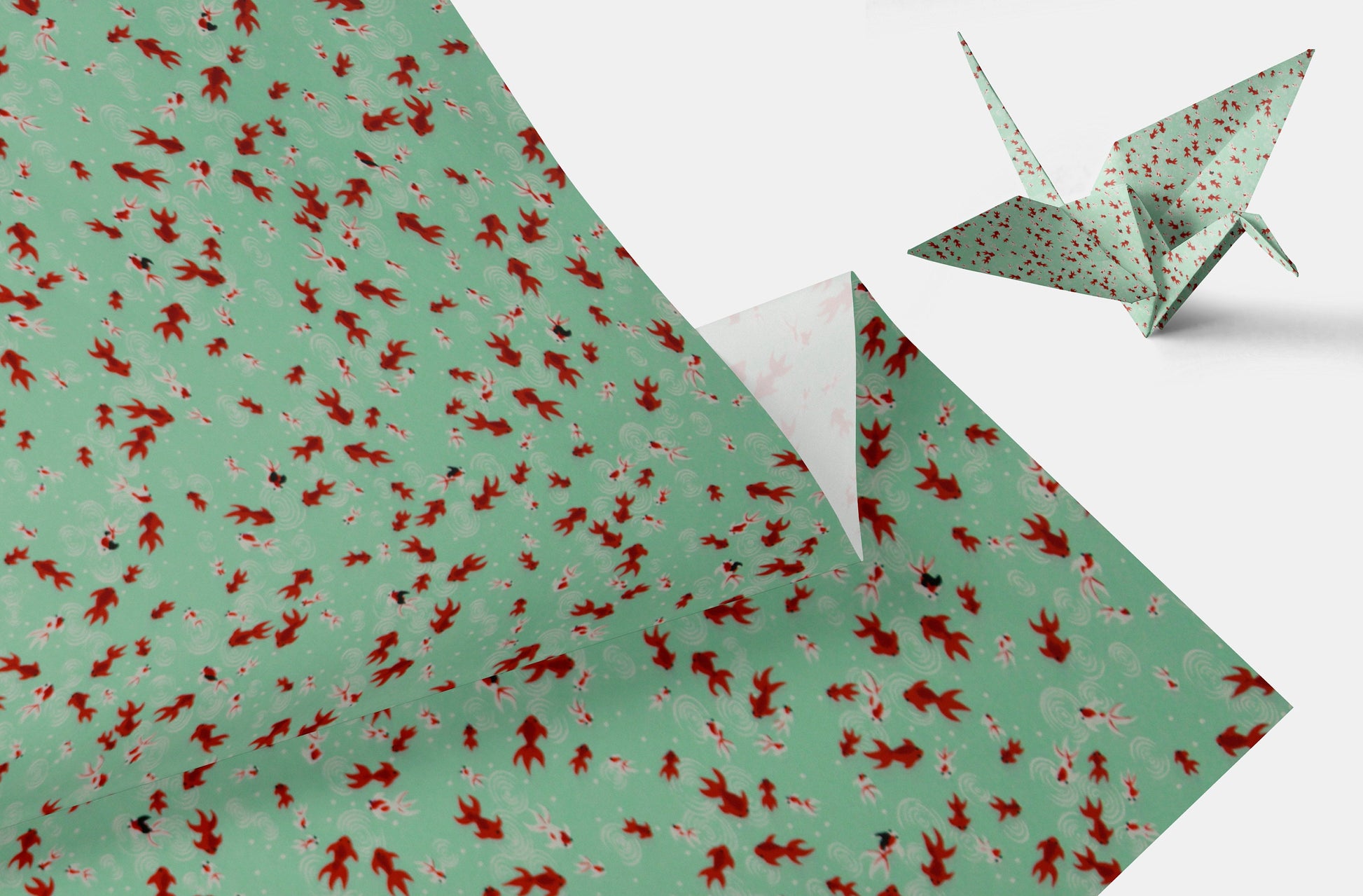 Green paper with red floral pattern and a folded green origami crane on a white background