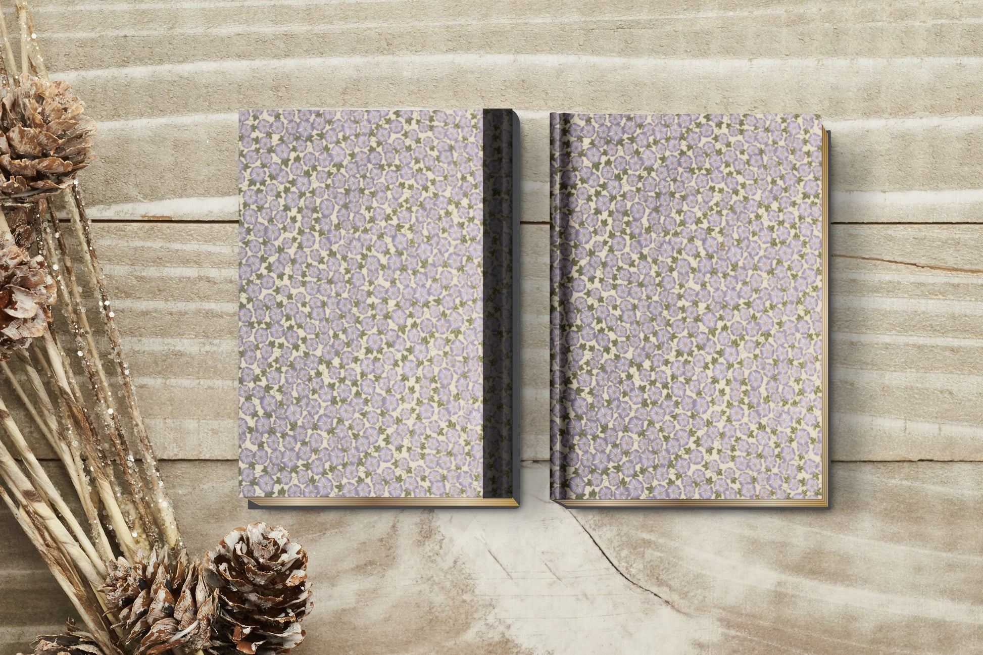 Two patterned notebooks made with chiyogami paper in a bookbinding project on a wooden surface with decorative elements.