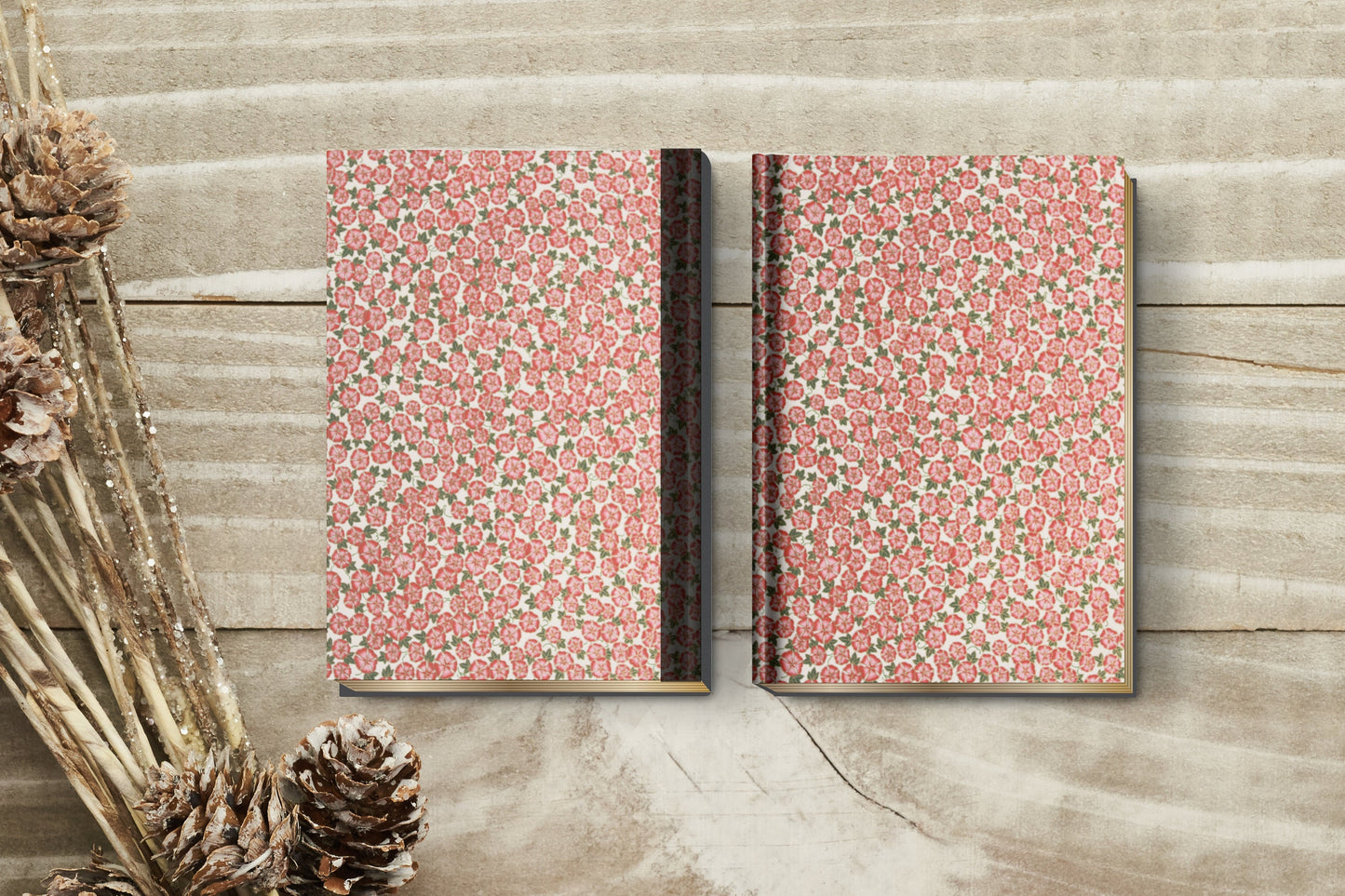 Two floral-patterned notebooks made with chiyogami paper in a bookbinding project on a wooden surface with decorative elements.