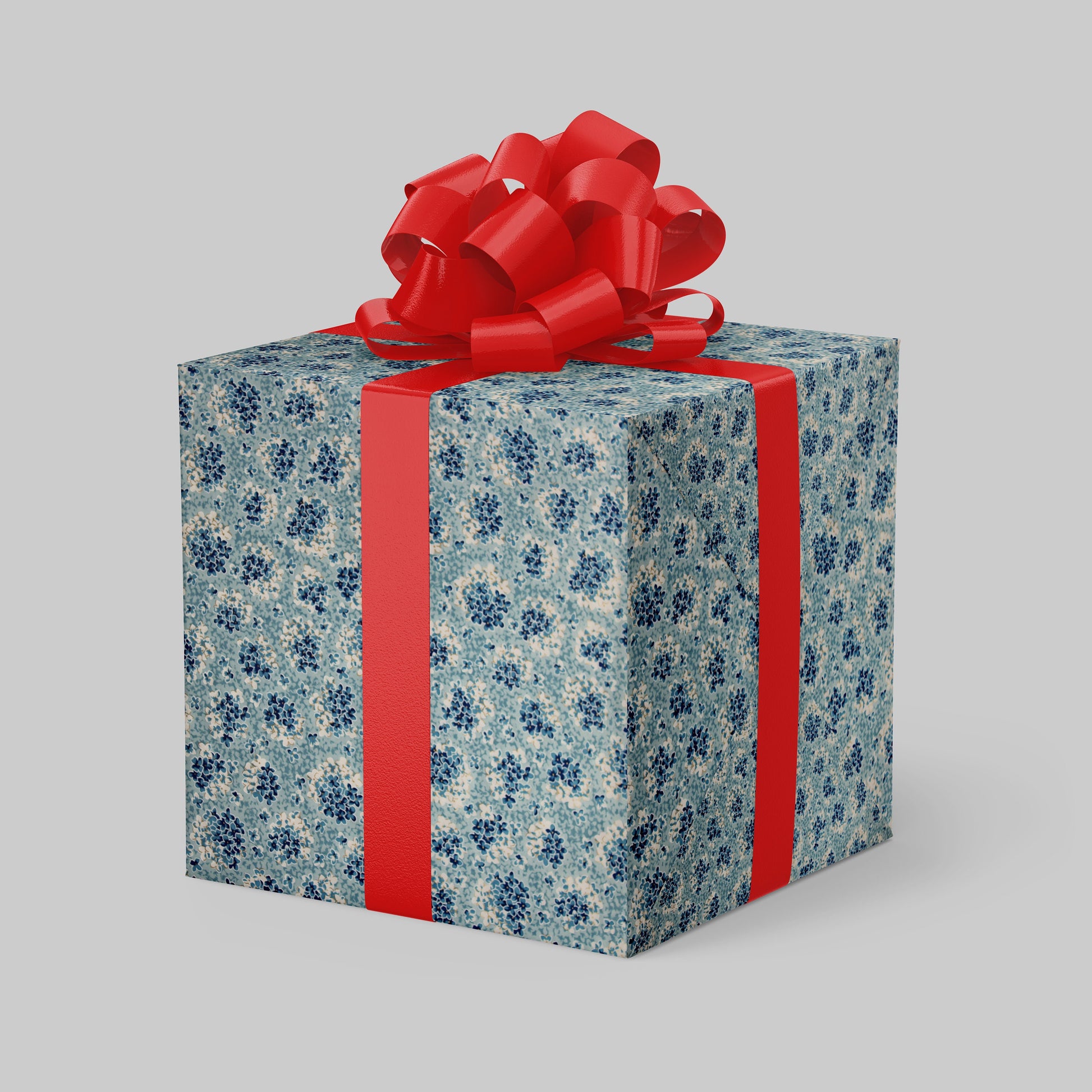 Gift box wrapped with chiyogami paper with blue floral pattern and red ribbon on a gray background