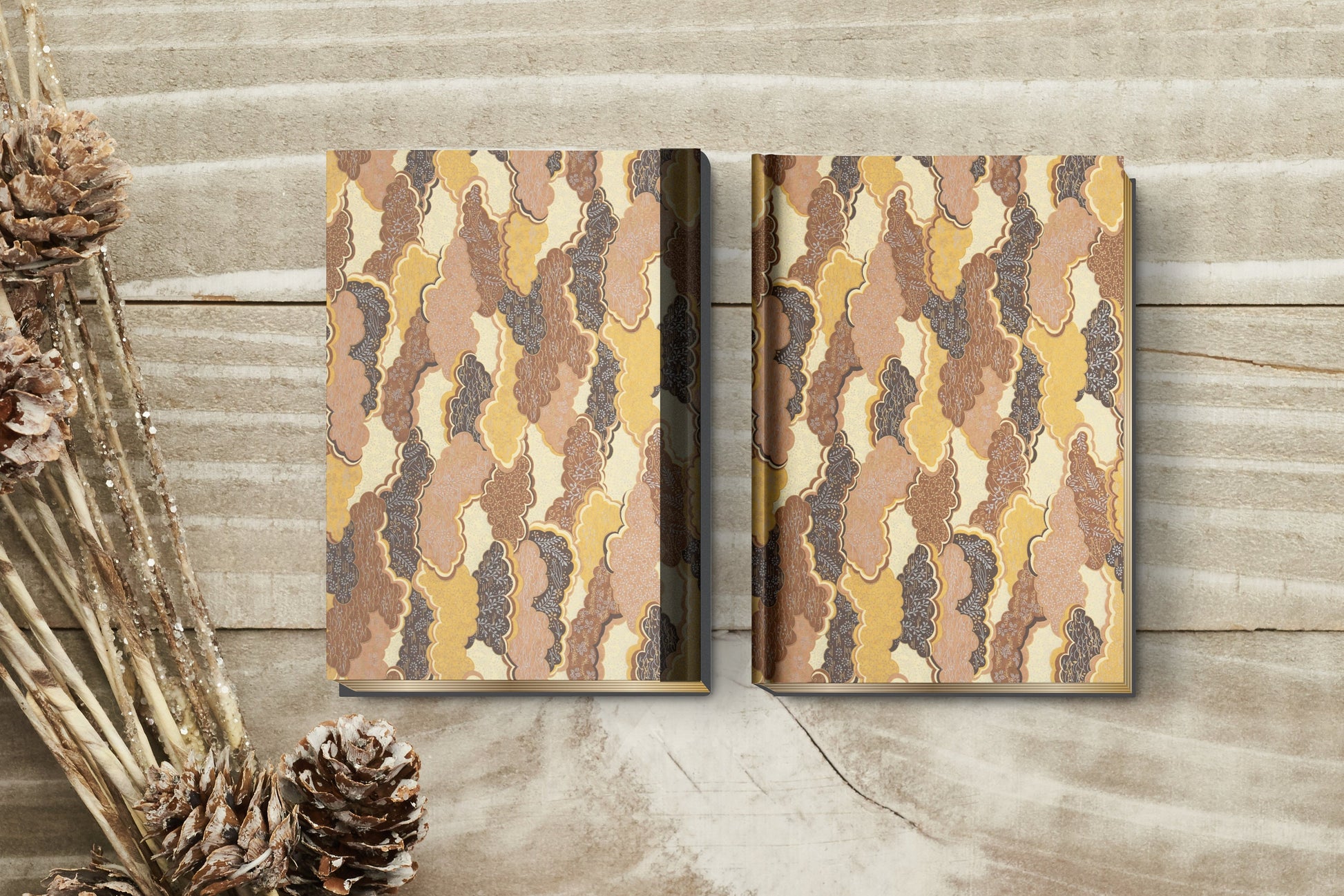 Two notebooks with a camouflage pattern made with chiyogami paper in a bookbinding project on a wooden surface.