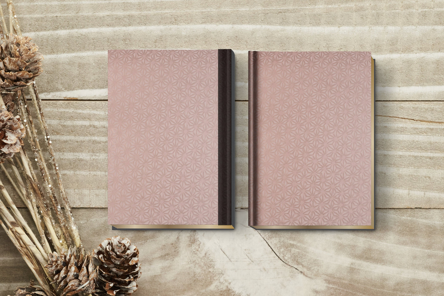 Two pink notebooks made with chiyogami paper in a bookbinding project on a wooden surface with decorative elements.