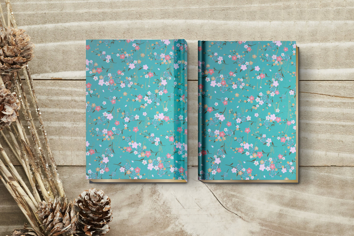 Two floral-patterned notebooks made with chiyogami paper in a bookbinding project on a wooden surface with decorative elements.