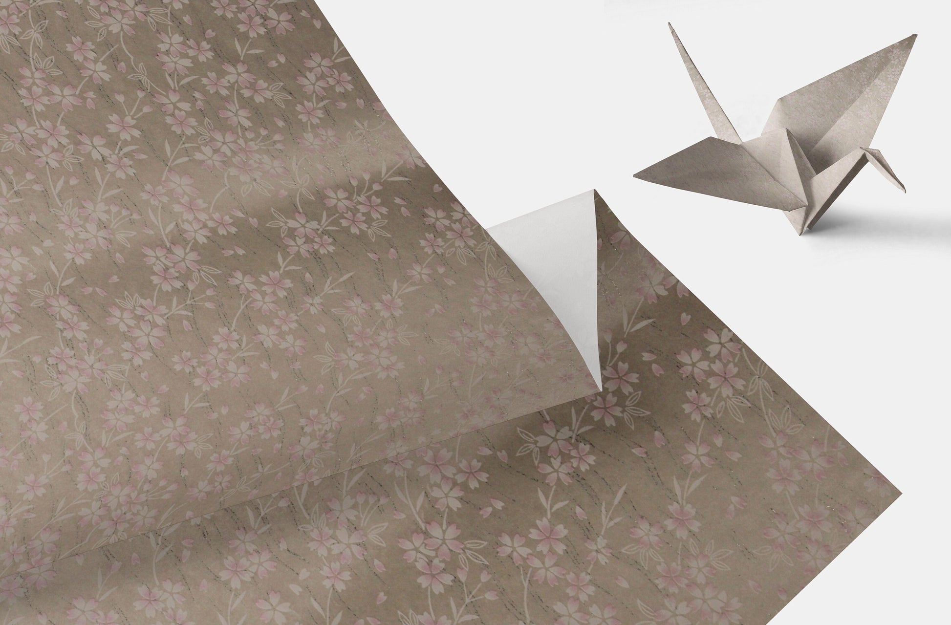 Floral-patterned chiyogami paper with a folded origami crane on a light gray background