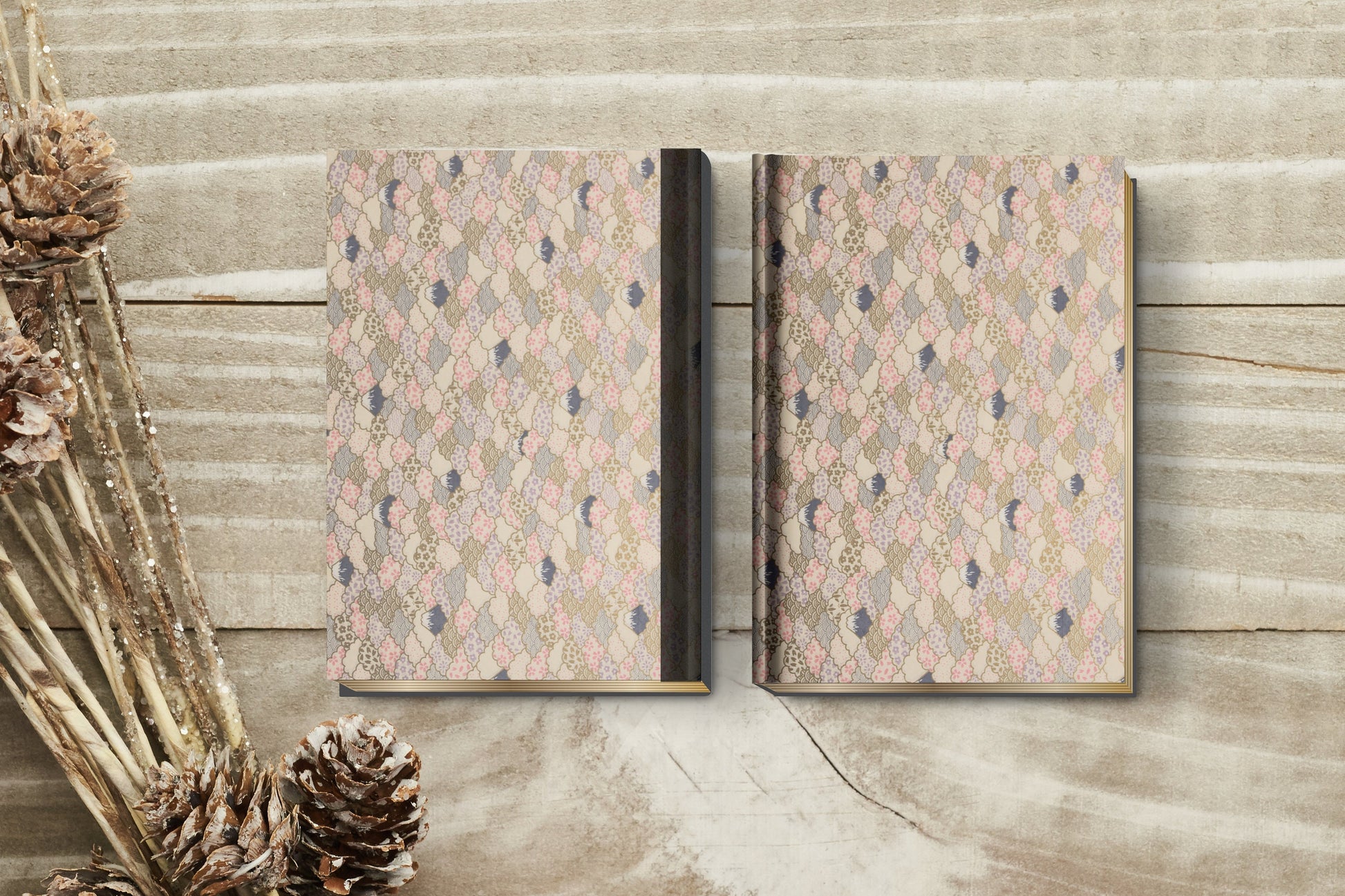 Two patterned books made with chiyogami paper in a bookbinding project on a wooden surface with decorative elements.