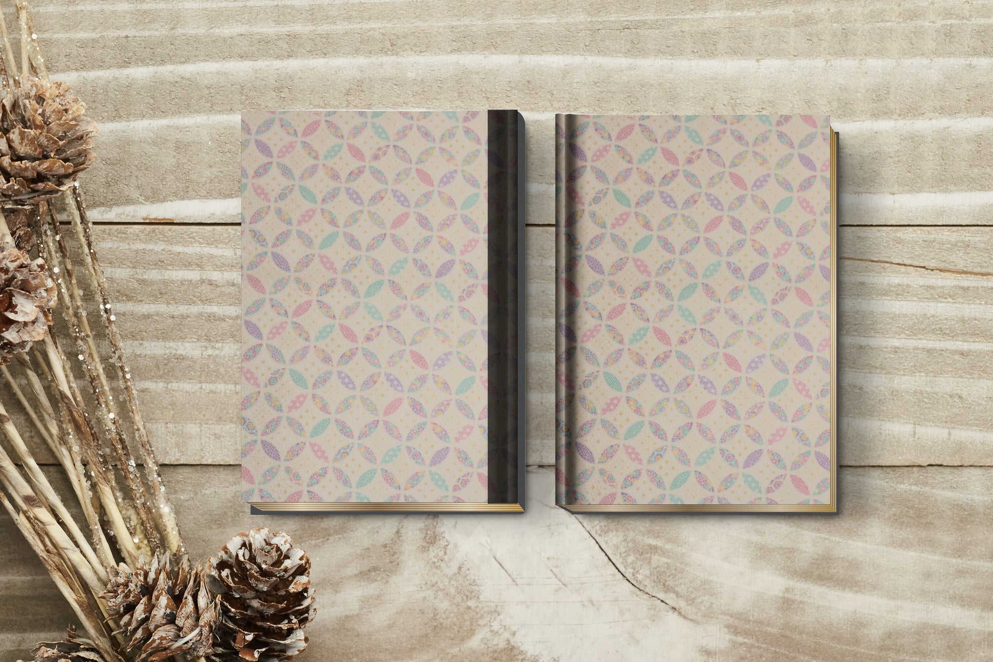 Two patterned notebooks made with chiyogami paper in a bookbinding project  on a wooden surface with decorative elements.