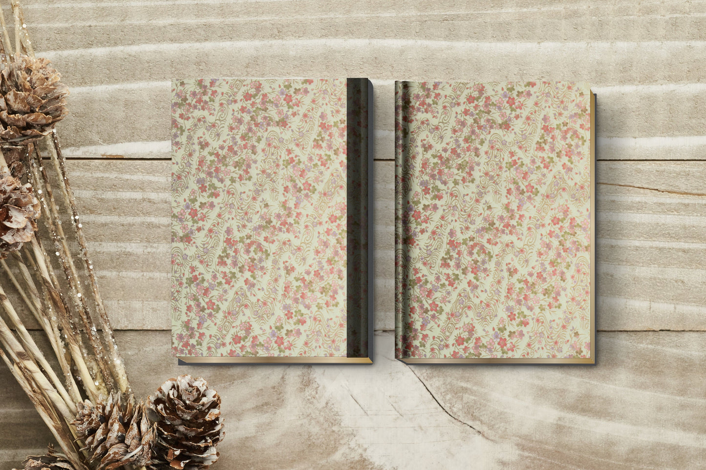 Two floral-patterned books made with chiyogami paper in a bookbinding project on a wooden surface with decorative elements.