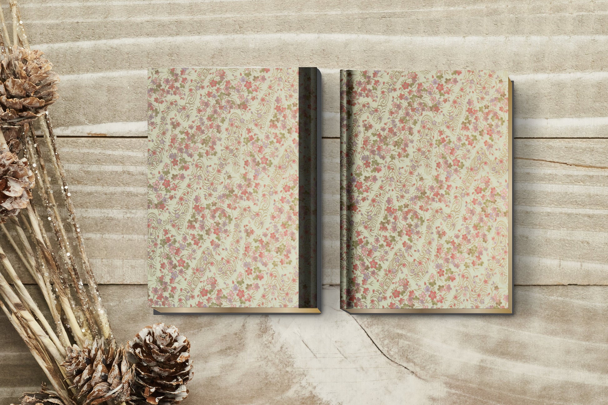 Two floral-patterned books made with chiyogami paper in a bookbinding project on a wooden surface with decorative elements.