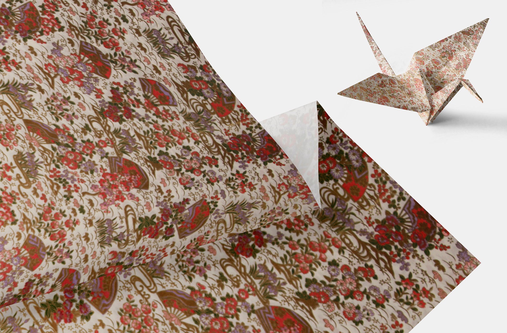 Floral-patterned chiyogami paper with a folded origami crane on a white background