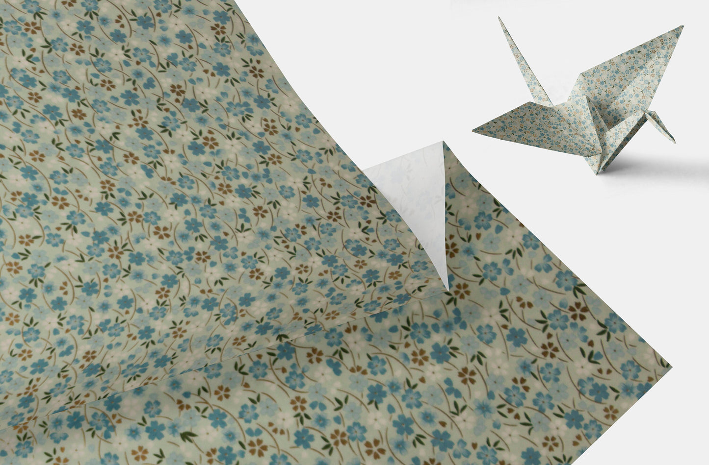 Floral-patterned chiyogami paper with a folded corner and an origami crane on a white background