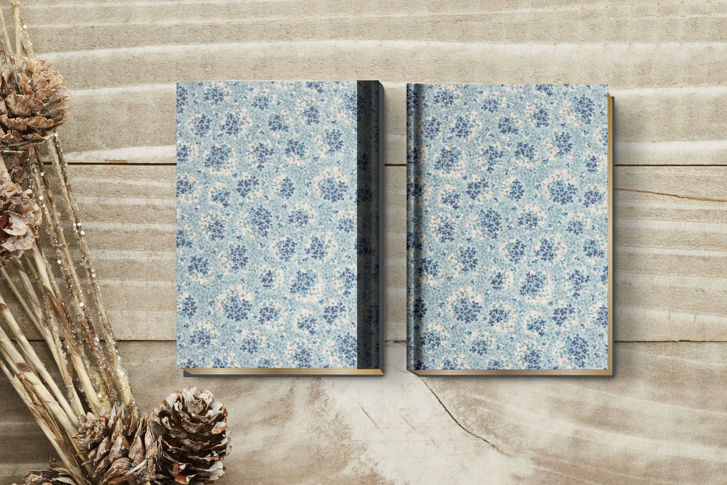 Two floral-patterned books made with chiyogami paper in a bookbinding project on a wooden surface with dried plants.
