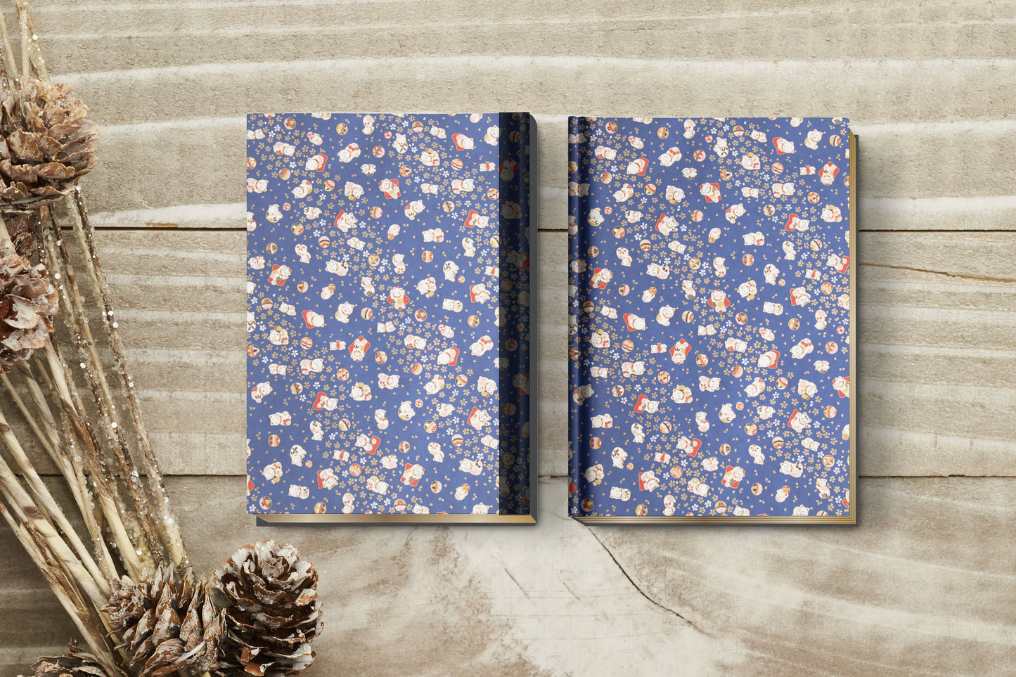 Two floral-patterned notebooks made with chiyogami paper in a bookbinding project on a wooden surface with dried plants.