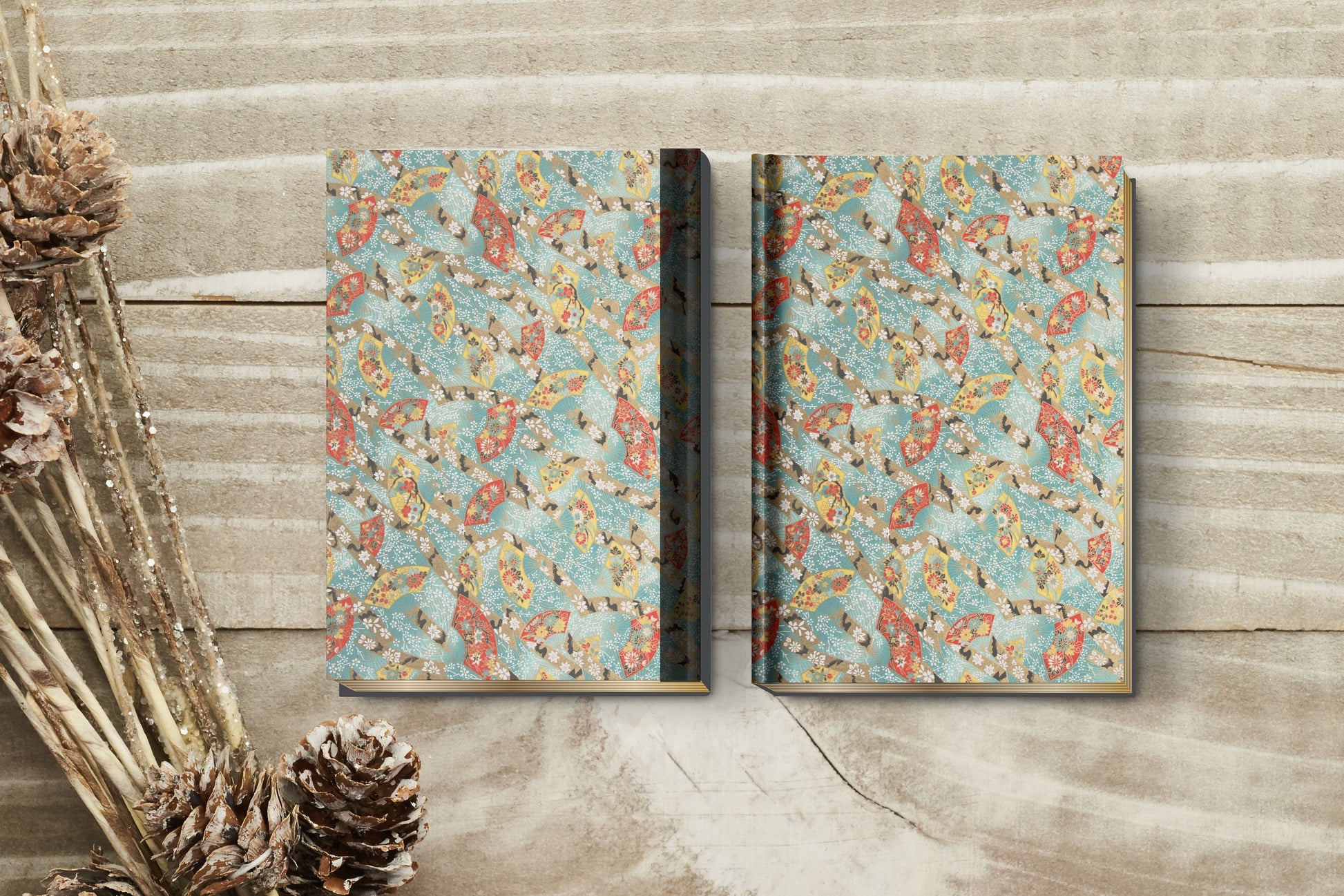 Two floral-patterned books made with chiyogami paper in a bookbinding project on a wooden surface with decorative elements.