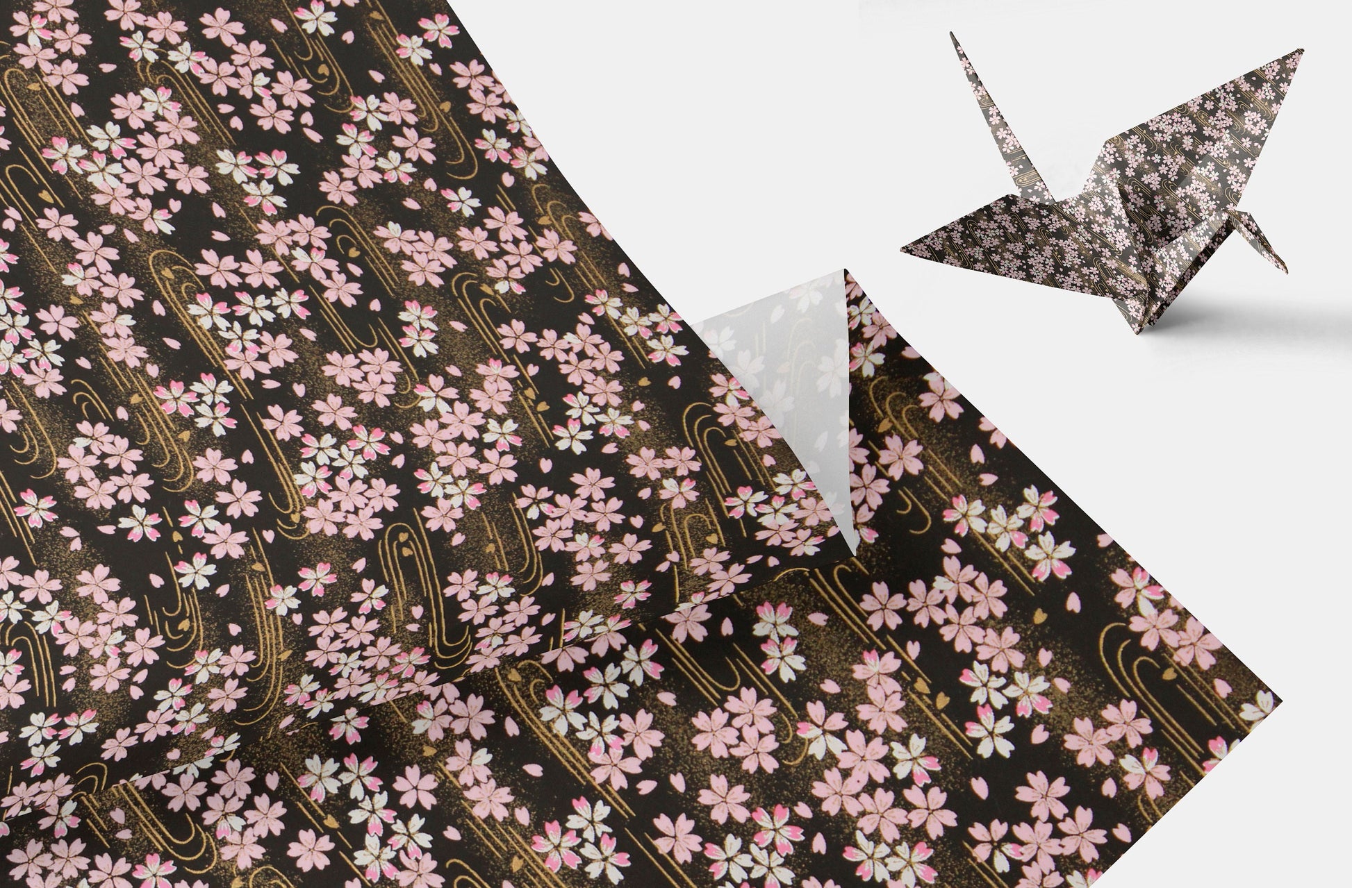 Floral-patterned paper with a folded corner and an origami crane on a white background