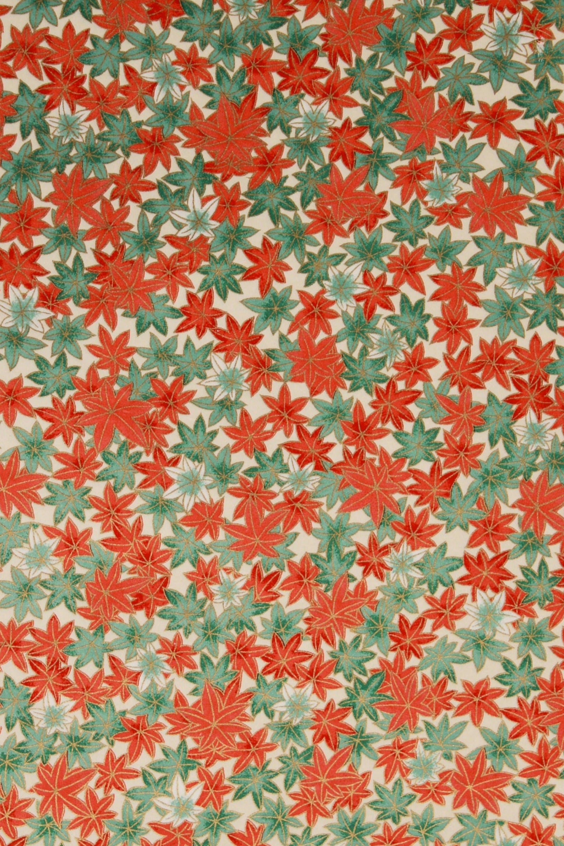 Patterned chiyogami paper with red and green leaves on a beige background